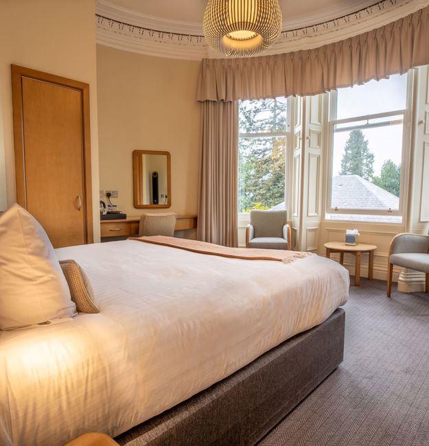 Room with double bed facing big windows
